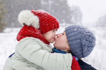 A mother is kissing her daughter.