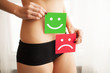 Woman Health Problem. Closeup Of Female With Fit Slim Body In Panties Holding Two Card With Sad Smiley And Happy Face Near Her Stomach. Digestive Disorders, Period Pain, Health Issues Concept