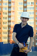 © yarohork - Smiling man in helmet stands at front of building construction