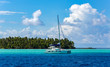 Lonely catamaran in the turquoise lagoon on the background of the island of Tahaa in the Leeward group of the Society Islands of French Polynesia.