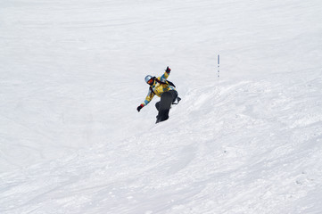 Snowboarder jumping on snowy ski slope at high winter mountains