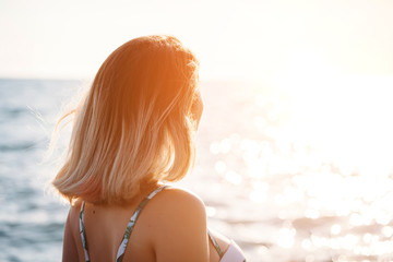 Portrait of a beautiful smiling young woman in bikini on the beach. Female model posing in swimsuit on sea shore. Summer holidays, travel, people and vacation concept.