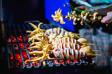 Grilled squid seller in local street food at Yaowarat road famous tourist place in Thailand