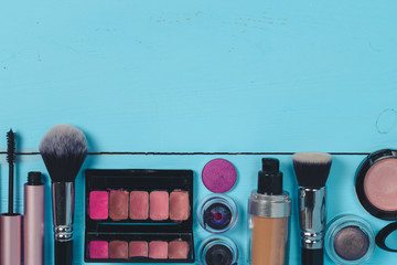 topview of set of different make up cosmetics and brushes on wooden blue background. Texture. flat lay.