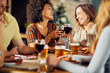 © chika_milan - Friends making a toast while sitting in restaurant. Multi-ethnic group.
