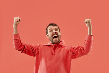 Wall Mural - I won. Winning success happy man celebrating being a winner. Dynamic image of caucasian male model on coral studio background. Victory, delight concept. Human facial emotions concept. Trendy colors