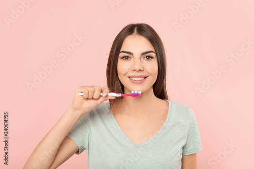 Fotografía Beautiful woman brushing teeth on color background