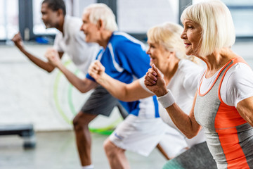 Wall Mural - selective focus of senior sportswoman exercising with friends at gym