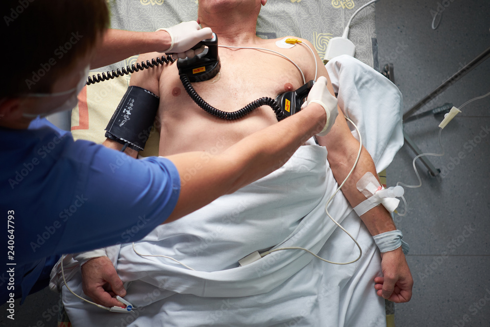 Doctor intensivist performs defibrillation to critical patient - obrazy, fototapety, plakaty 