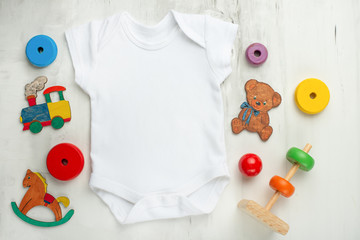 Layout Flat Lay white baby shirt bodysuit on, white background with children's toys. Mock up for the design and placement of logos.