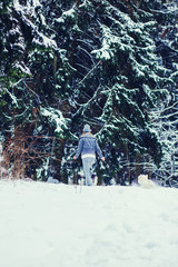 Young woman with her dog walking in the winter forest