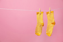 Cute Socks On Laundry Line Against Color Background. Space For Text
