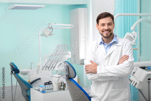 Obraz Dibond Fachowy męski dentysta w białym żakiecie w miejscu pracy. Miejsce na tekst