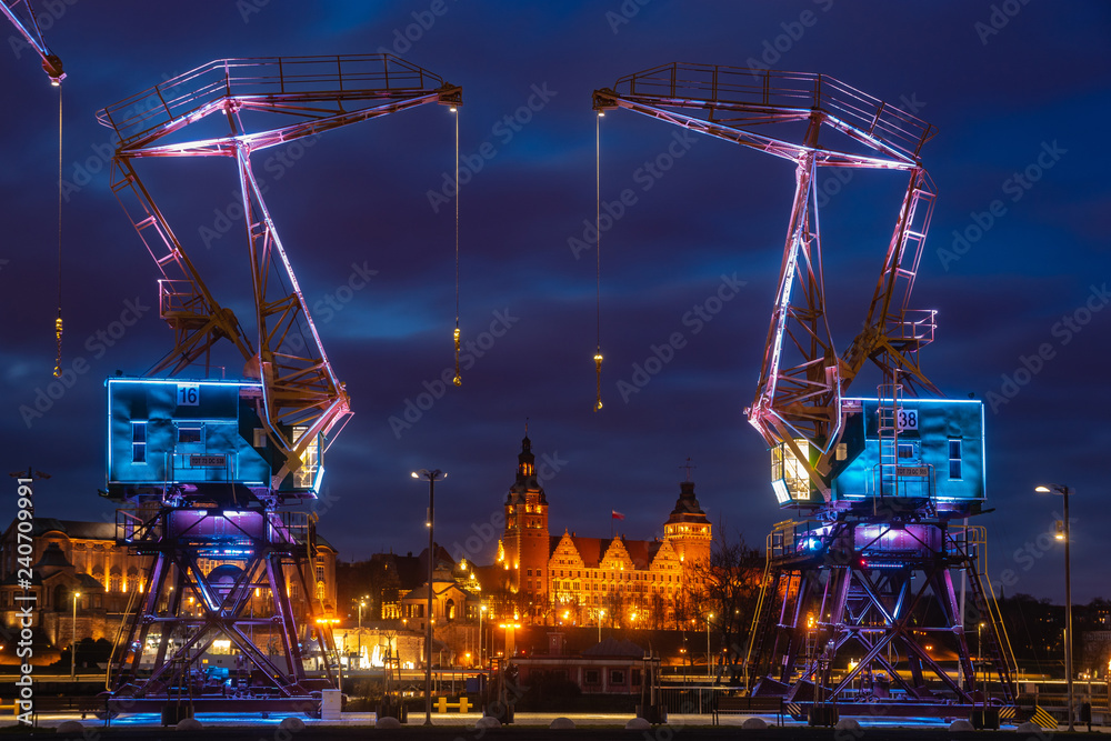 Illuminated old port cranes on a boulevard in Szczecin City at night - obrazy, fototapety, plakaty 
