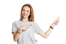 Happy Lady Looking Camera And Pointing To The Right. Portrait Of A Young Woman Shows Fingers In The Direction Of The Space For Text.