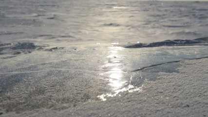 Wall Mural - wind carries snowflakes on the ice. the sun is reflected on the smooth surface of the ice.
