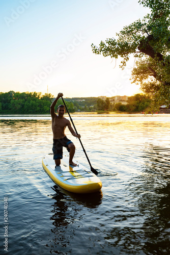 Foto Joyful multiracial guy paddling on a SUP board