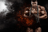 Brutal strong muscular bodybuilder athletic man pumping up muscles with chains on black background. Workout bodybuilding concept. Copy space for sport nutrition ads.