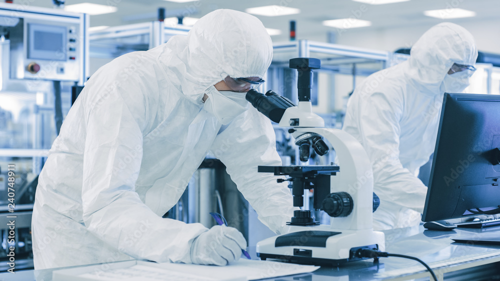 In Laboratory Scientists in Protective Clothes Doing Research, Using Microscope and Entering Data into Personal Computer. Modern Manufactory Producing Semiconductors and Pharmaceutical Items. - obrazy, fototapety, plakaty 
