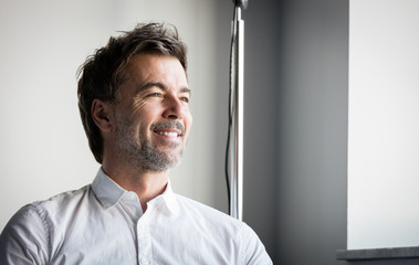 Wall Mural - A smiling middle-aged bearded man looking at the window at the hotel