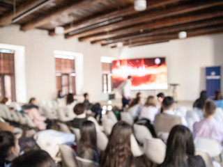 Education concept, blurred students and businessmen and women studying in large hall with screen and projector for showing information people teacher room presentation.