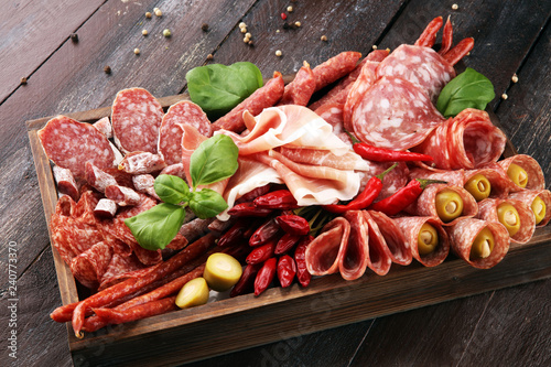 Fotografie, Obraz Food tray with delicious salami, pieces of sliced prosciutto crudo, sausage and basil