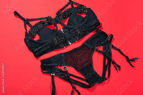 Zdjęcie XXL Bielizna bdsm czarna na czerwonym tle. Seksowne majtki i biustonosz akcesoria do sprawdzania płci na szyi