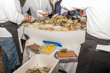 Wall Mural - Two people clean oysters from shells for visitors