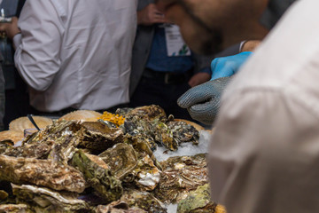 A man delivers oysters on plates to visitors in iron gloves with a calculus.