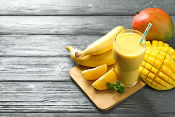 Tasty tropical drink with mango and fresh fruits on wooden table. Space for text