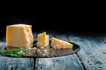 Pieces of parmesan or parmigiano cheese on a wooden dark board