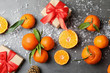 Christmas composition with ripe tangerines and gift boxes on grey background, flat lay