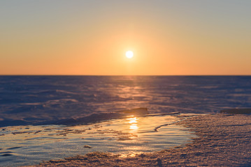 Wall Mural - transparent fragments of ice against the backdrop of the endless snowy landscape during sunset.