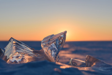 Wall Mural - transparent fragments of ice against the backdrop of the endless snowy landscape during sunset.