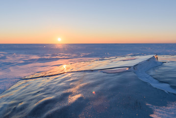 Wall Mural - transparent fragments of ice against the backdrop of the endless snowy landscape during sunset.