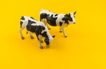 Toy Cow Made Of Plastic On A Yellow Background.