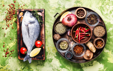 Wall Mural - Fresh uncooked dorado fish with herbs and spices on rustic wooden board.Cooking concept