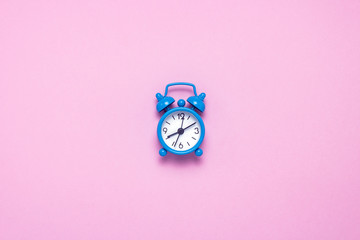 Blue alarm clock on a pink background. Concept day and night, time management, planning, schedule of day and night, minimalism. Flat lay, top view