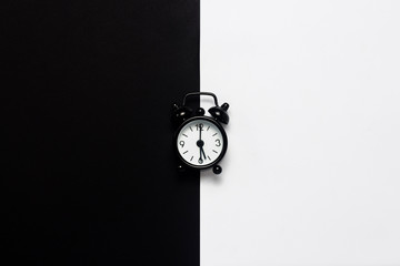 Black alarm clock on a black and white background. Concept day and night