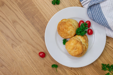 Egg buns on white plate with parsley and mini tomatoes on wooden background with white and blue towel