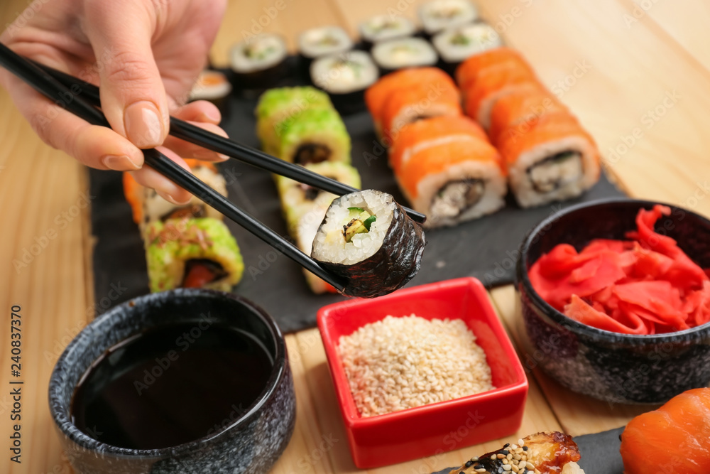 Woman eating tasty sushi at table