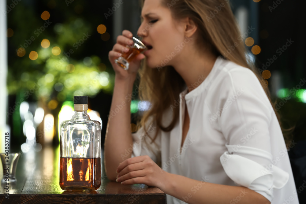 Depressed woman drinking alcohol in pub