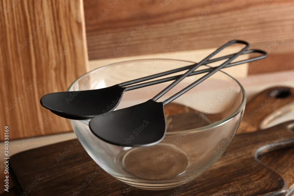 Spoons with glass bowl and wooden boards on table