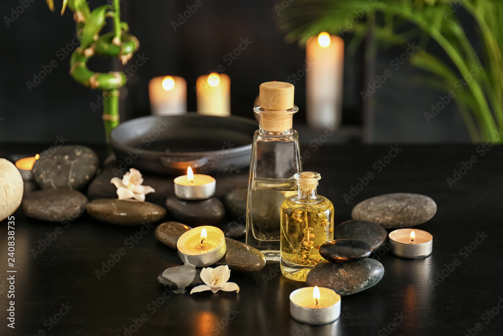 Essential oil, spa stones and candles on dark background