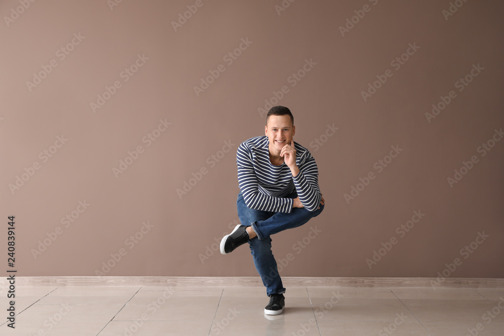 Young man dancing near color wall