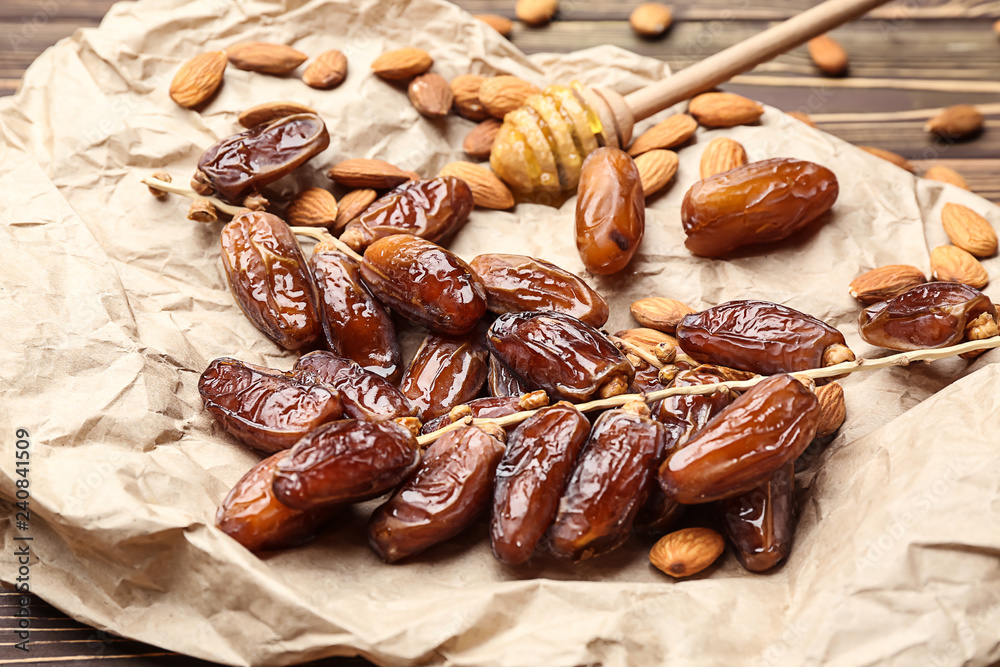 Sweet dried dates with almonds and honey dipper on table