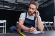 © LIGHTFIELD STUDIOS - adult  handyman talking on smartphone and writing in clipboard while measuring floor