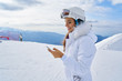© ZoomTeam - Attractive young woman at a mountain ski resort. Standing on a snow chatting on her mobile phone and laughing