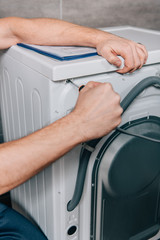 Wall Mural - cropped image of male handyman repairing washing machine in bathroom