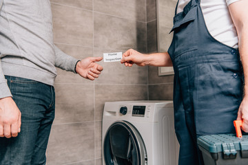 Wall Mural - cropped image of male handyman giving card with lettering home inspection to owner in bathroom